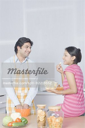 Mid adult woman looking at her husband preparing food