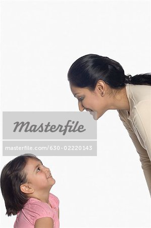 Mid adult woman and her daughter looking at each other