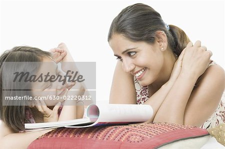 Young woman with her daughter lying on the bed and smiling