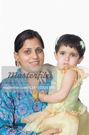 Portrait of a mid adult woman carrying her daughter and smiling