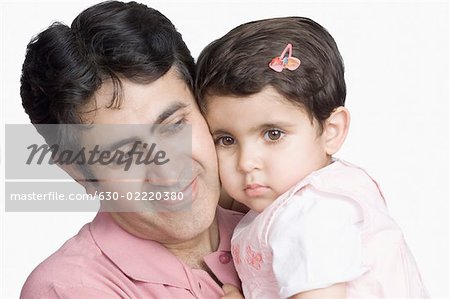 Close-up of a mid adult man cheek to cheek with his daughter