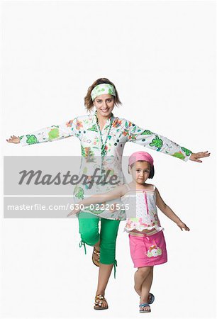 Portrait of a young woman and her daughter standing with their arms outstretched