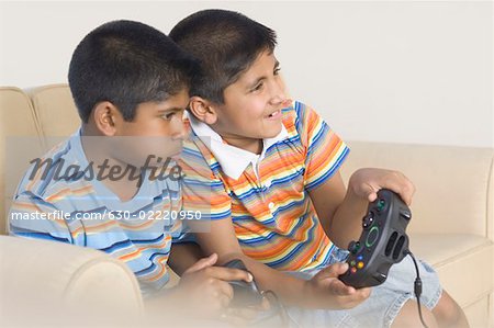 Two boys sitting on a couch and playing video game