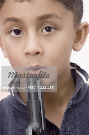 Portrait of a boy blowing in a gun barrel