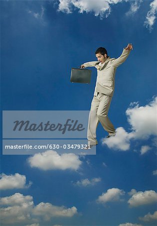 Businessman holding a briefcase and moving on clouds