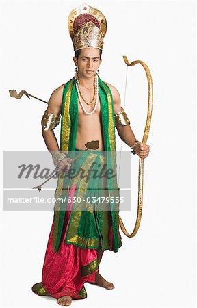 Young man in a character of Arjuna and holding a bow and arrow