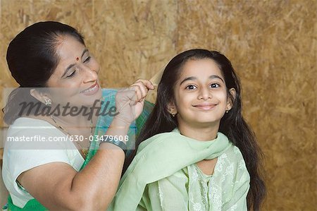 Mature woman combing hair of her granddaughter