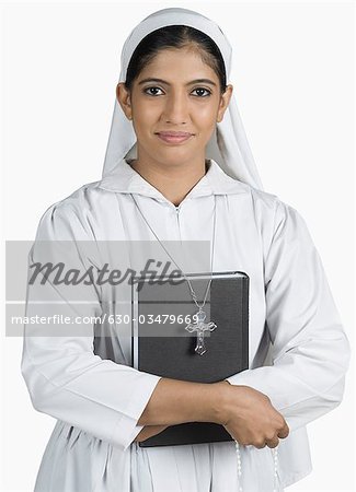 Portrait of a nun standing with her arms crossed and holding the Bible