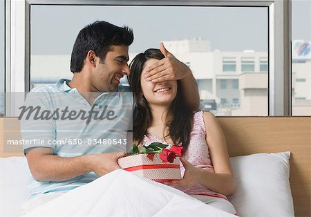 Man giving a present to his girlfriend on the bed