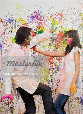 Couple dancing in front of a wall colored with Holi colors