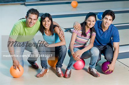 Two young couples with bowling balls in a bowling alley