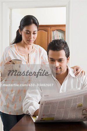 Couple reading a newspaper with cup of coffee