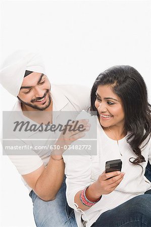 Woman using a mobile phone with her husband sitting beside her