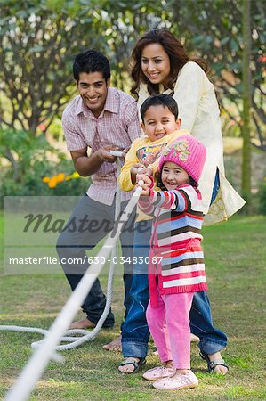 Couple with their children playing tug-of-war in a park