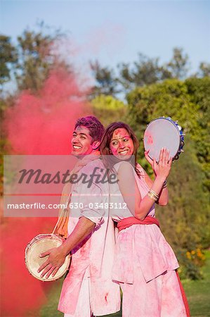 Couple celebrating Holi with colors and musical instruments