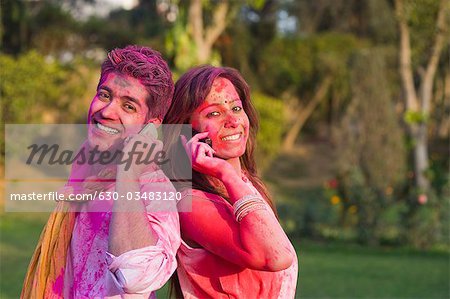 Couple in Holi colors talking on mobile phones