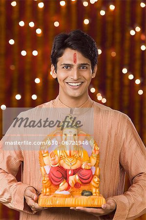 Portrait of a man holding an idol of lord Ganesha