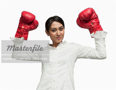 Businesswoman in boxing gloves cheering with arms raised