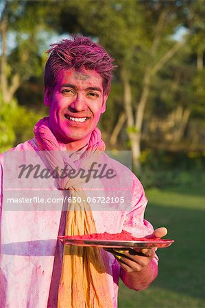 Man holding a plate of powder paint on Holi