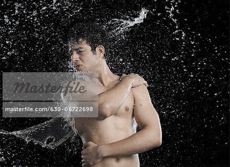 Bare chested man splashed with water