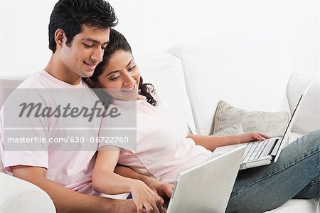 Couple working on laptops on a couch