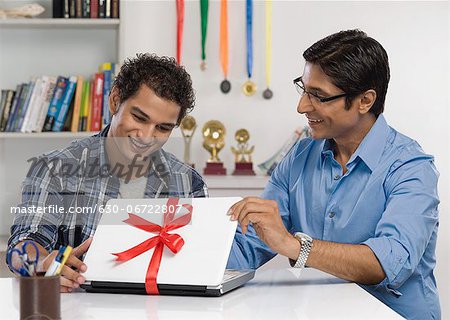 Man gifting a laptop to his son