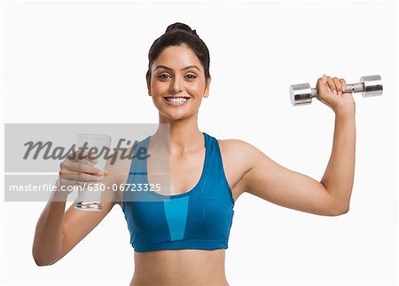 Woman holding a glass of milk and exercising with a dumbbell