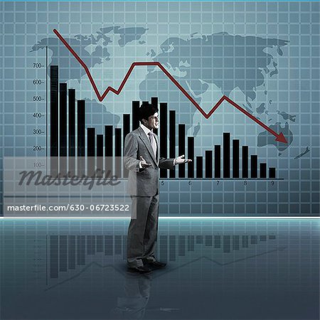 Businessman standing in front of a line graph moving downward