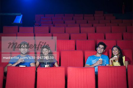 Couple enjoying soft drinks while watching movie in a cinema hall
