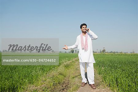 Farmer talking on a mobile phone in the field, Sonipat, Haryana, India Farmer talking on a mobile phone in the field, Sonipat, Haryana, India