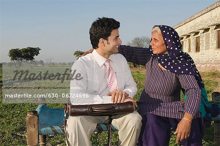 Businessman sitting with his mother in the field, Sonipat, Haryana, India Businessman sitting with his mother in the field, Sonipat, Haryana, India