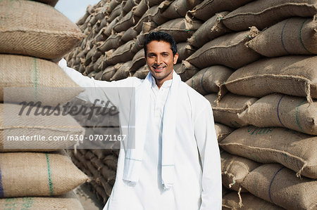 Man standing near stacks of wheat sacks in a warehouse, Anaj Mandi, Sohna, Gurgaon, Haryana, India