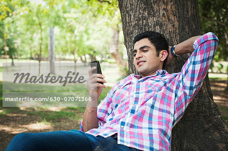 Man text messaging on a mobile phone in a park, Lodi Gardens, New Delhi, Delhi, India