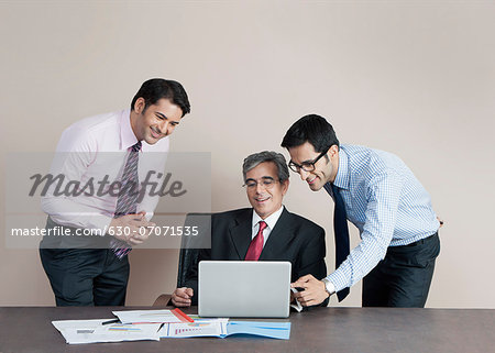 Business executives looking at a laptop and smiling