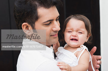 Man carrying his crying daughter
