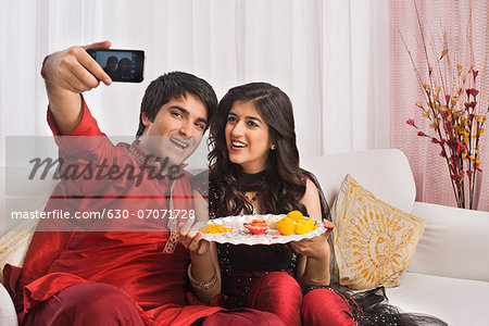 Brother and sister taking a picture of themselves with a mobile phone at Raksha Bandhan