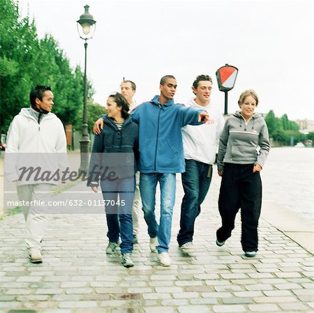 Six young people walking together on cobblestones