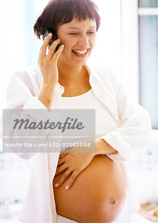 Pregnant woman using cell phone, smiling