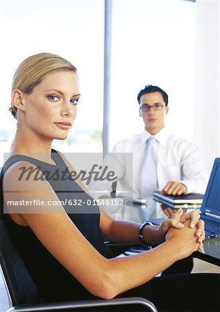 Businessman and woman sitting in office, portrait