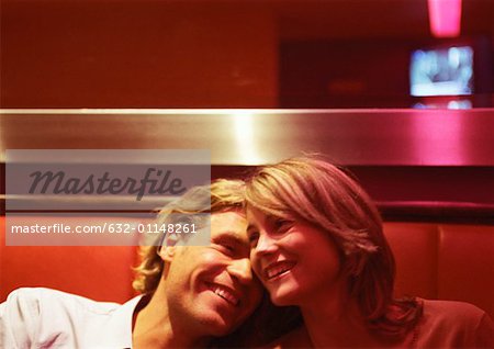 Man and woman laughing, heads together, close up.