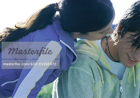 Teenagle girl whispering in boyfriend's ear, close up
