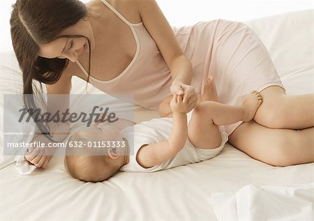 Baby and mother on bed, holding hands
