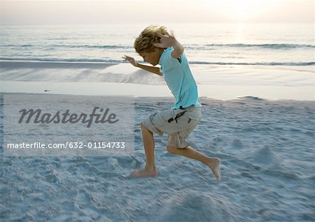 Boy jumping on beach, side view