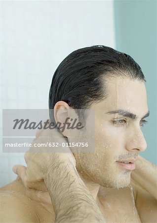 Man with hands behind neck in shower