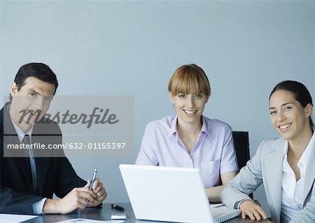 Business colleagues gathered around laptop, smiling