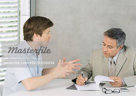 Young man speaking to mature businessman and gesturing