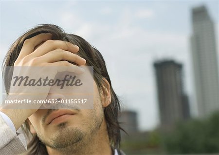 Young businessman holding head and closing eyes