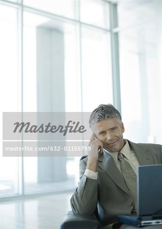 Businessman using cell phone and laptop in lobby