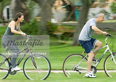 Mature couple riding bikes, side view