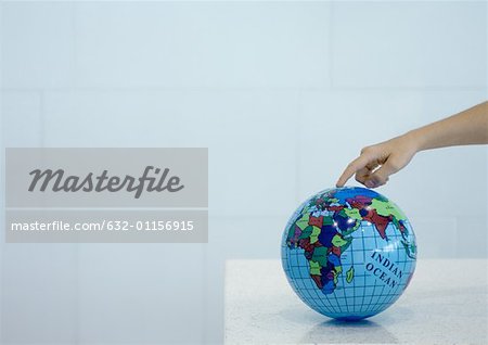 Child's hand pointing to spot on globe